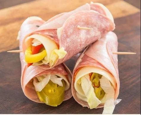 Grain-free Italian Sub Roll-Up served on a wooden board with fresh ingredients.