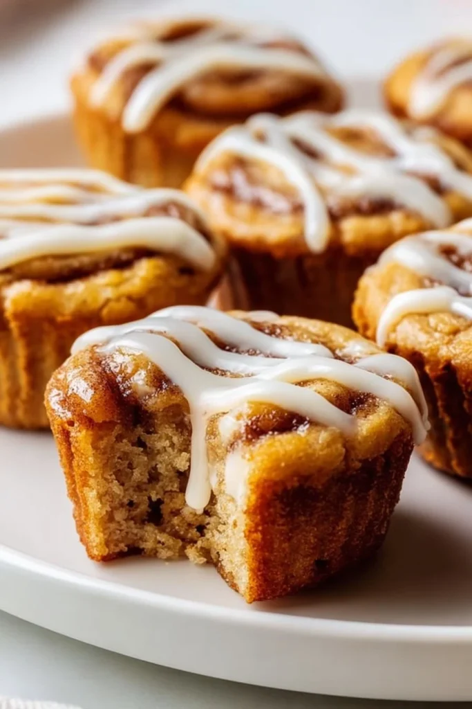 Delicious cinnamon roll protein muffins on a wooden table with cinnamon sticks