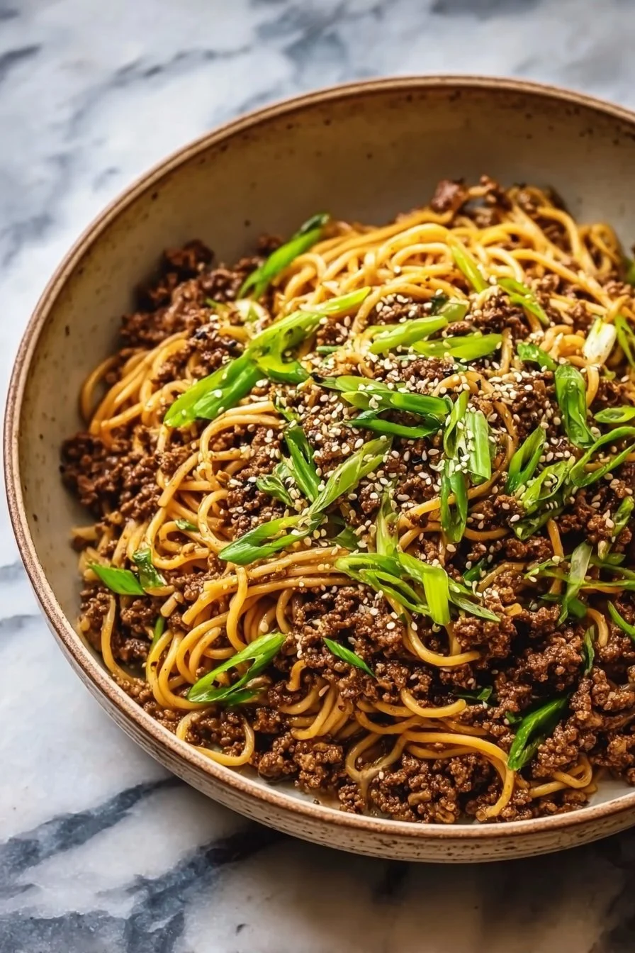 Delicious Mongolian ground beef noodles served in a bowl with vegetables.